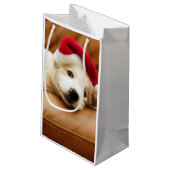 Welpe trägt einen Weihnachtshut und das Lügen auf Kleine Geschenktüte (Rückseite Schrägansicht)