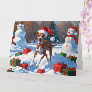 Windhund läuft im Schnee mit Weihnachtsmütze Karte
