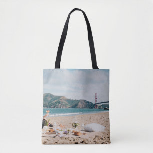 Woman sitting near seashore while looking at Golde Tasche