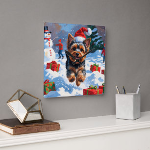Yorkshire Terrier im Schnee mit Weihnachtsmütze Quadratische Wanduhr
