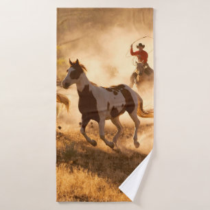 Zwei Western Cowboys reiten Pferde und springen wi Badehandtuch