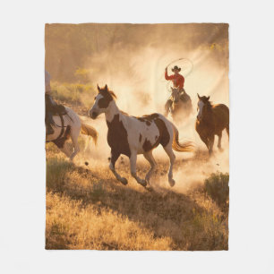Zwei westliche Cowboys reiten Pferde und werfen wi Fleecedecke